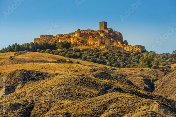 Fototapeta A picturesque view of the abandoned, old mountain town of Craco, built of sandstone rock. Craco is a ghost town abandoned due to an earthquake in the late 20th century. Province of Matera, Basilicata,