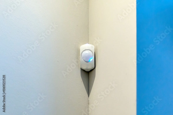 Fototapeta Alarm system presence detector on a wall with space for text with white background and blue right side