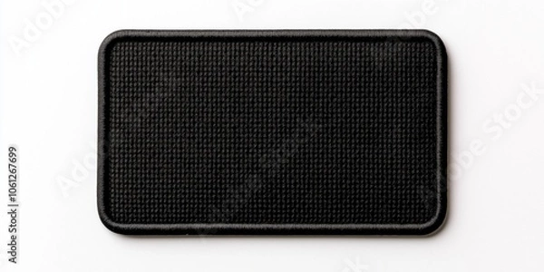 Fototapeta This image showcases a simple, black rectangular textile patch with a textured surface, neatly placed on a smooth white background, ideal for various uses in design.