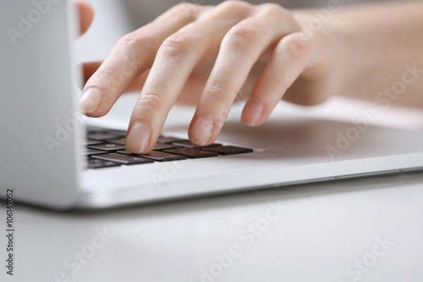 Obraz Female hands using laptop on white wooden table, close up