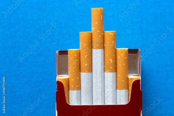 Fototapeta top view of an opened packet with cigarettes on blue background