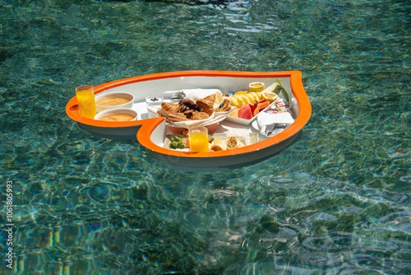 Fototapeta Floating heart-shaped plate with a breakfast of fruits, rice, fish, buns, juice  in the swimming pool in the Maldives