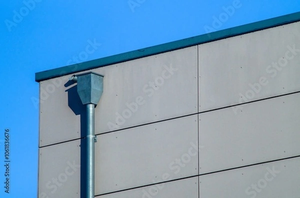 Fototapeta Downspout draining water from roof into gutter system on building exterior