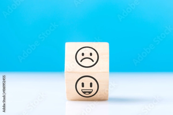 Fototapeta Wooden blocks displaying a sad face transitioning to a happy face, symbolizing a shift from negativity to positivity. Final block turns from sad to happy, highlighting the power of a positive outlook