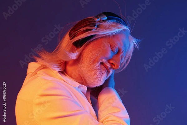 Fototapeta elderly man enjoying music, headphones, vibrant colors, emotional expression, blue and pink background, relaxed atmosphere, peaceful vibes, close up portrait, carefree moment