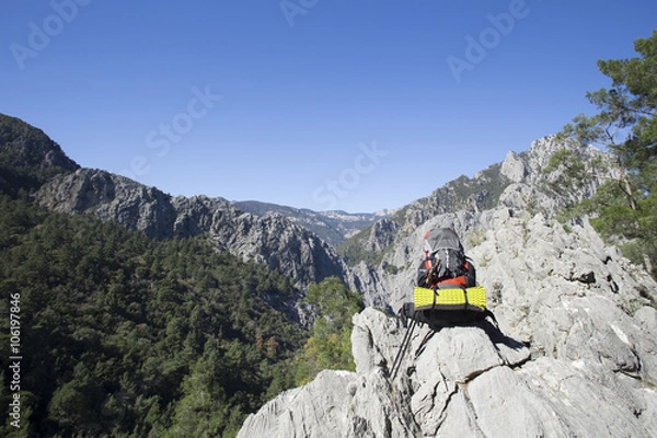 Fototapeta Backpack standing on top of a mountain.
