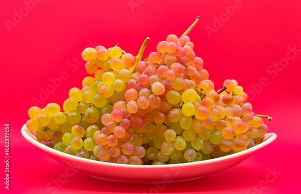 Obraz Plate with kishmish (sultana) grapes on a red background
