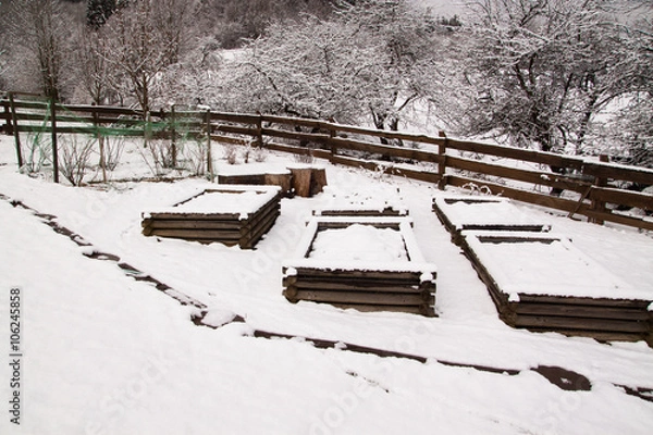 Obraz resting snow covered raised vegetable beds in the cold winter in countryside garden