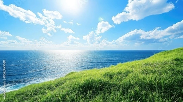 Obraz A peaceful seaside landscape shot with grassy hills sloping down to the ocean under a clear blue sky.