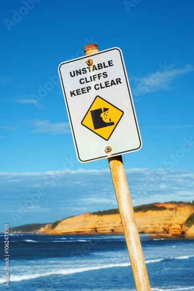 Fototapeta Unstable Cliffs Keep Clear sign with rocky coastline in distance