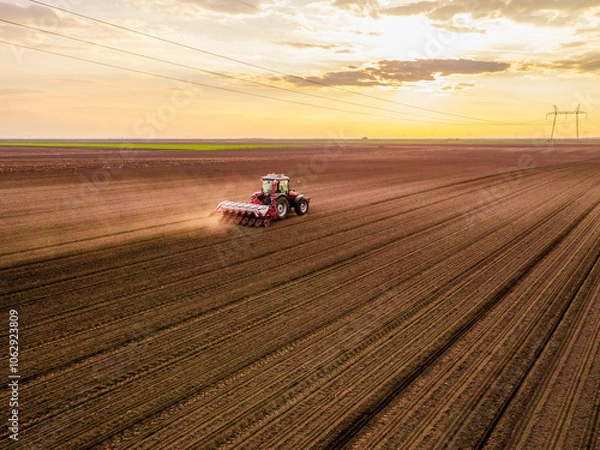 Obraz Aerial shot of a farmer seeding, sowing crops at field. Sowing is the process of planting seeds in the ground as part of the early spring time agricultural activities.
