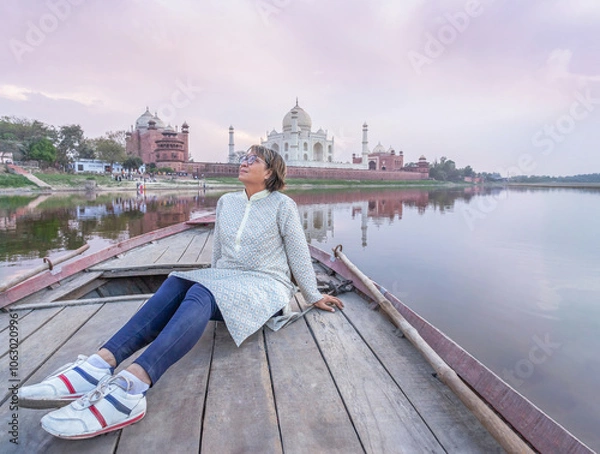 Obraz Woman enjoying beautiful sunset time on wooden boat ride in Yamuna river behind view Taj Mahal background