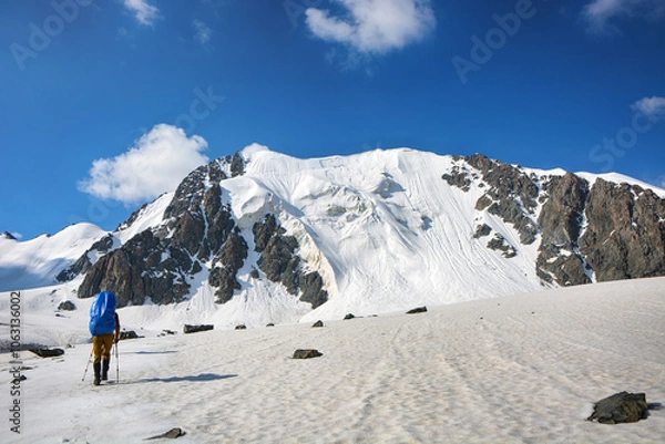 Fototapeta People go up to mountain on the glacier under clouds. High mountain view.