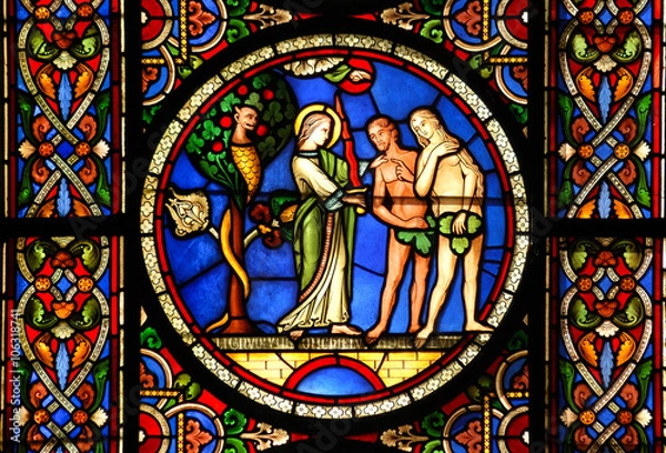 Fototapeta Stained glass window depicting Adam & Eve being tempted by the devil with the Angel warning them against temptation