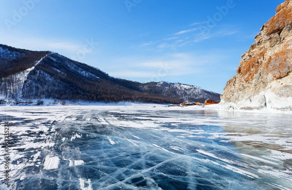 Fototapeta Baikal Lake on a sunny winter day. View from the ice road to the village of Uzury near the rocky shore of Olkhon Island. Winter ice travels and adventures