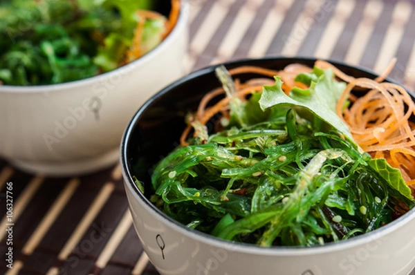 Obraz Two bowls of Japanese Chuka Wakame seaweed salad on bamboo mat, close-up