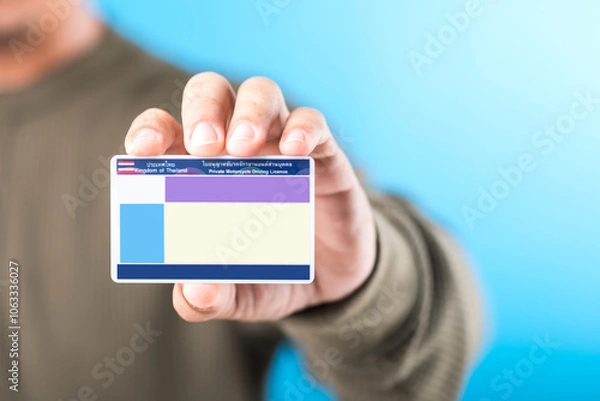 Obraz Thai man holds a blank Smart Card Thailand driver's license, emphasizing the importance of obtaining a license for road safety and responsible driving