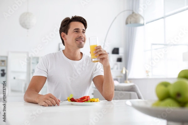 Fototapeta Good looking healthy man has breakfast at a table indoors.