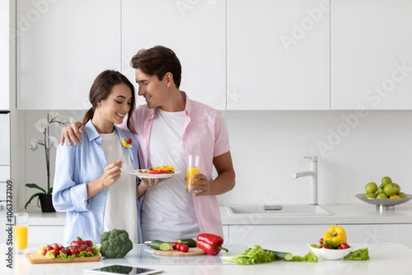 Obraz Couple in the kitchen having fun cooking vegetable breakfast, enjoying time together. Positive vegans