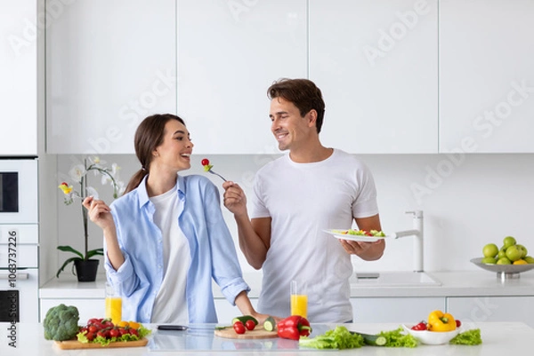 Obraz Couple in the kitchen preparing vegetable breakfast, enjoying time together. Positive vegans.