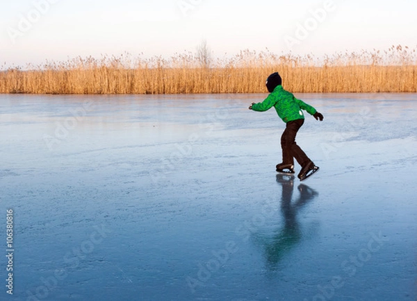 Fototapeta a boy skating on the frozen river