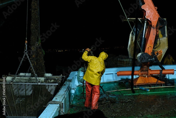 Fototapeta fisherman working on a mussel boat at night.