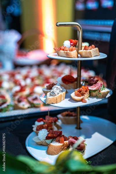 Fototapeta A variety of appetizers, including bruschetta, are displayed on a tiered serving stand. Perfect for catering, event promotions, or upscale dining, showcasing an elegant appetizer spread.