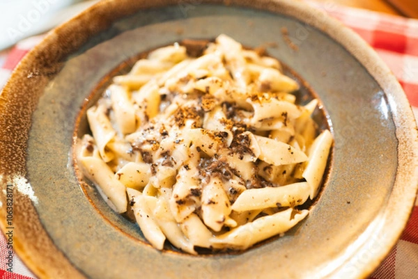 Fototapeta Creamy pasta garnished with shaved truffles, served on a rustic plate. Highlights gourmet appeal, great for fine dining promotions, Italian restaurant menus, or food blogs.