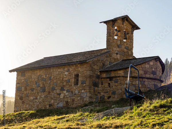 Fototapeta chapelle du lac de roselend avec banquette de télésiège posée devant. clocheton à deux cloches, patrimoine en pierre