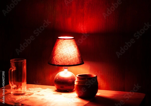 Fototapeta Red lamp and pot on table in dark