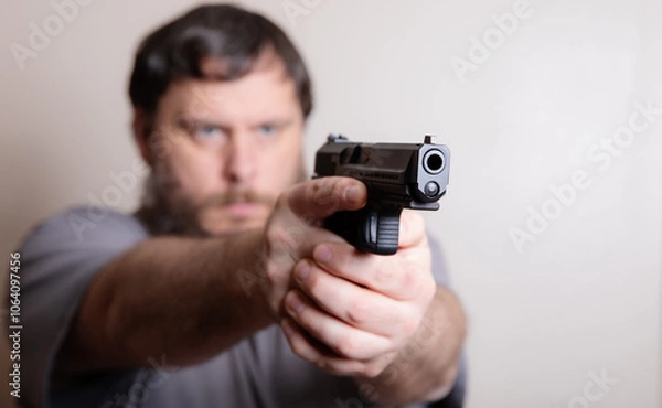 Fototapeta Man Aiming a Handgun with Intense Focus and Determination