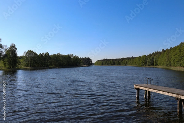 Fototapeta View of Lake Wydmińskie and the trees surrounding it, Wydminy, Poland, Warmian-Masurian Voivodeship