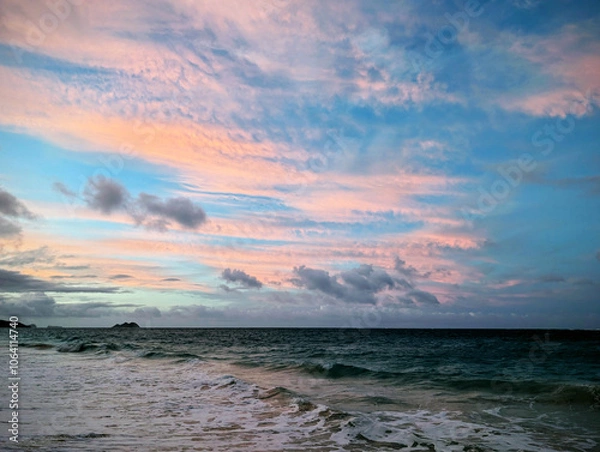 Fototapeta Golden hour clouds above the tranquil ocean waves at dusk on a serene beach