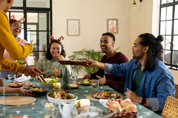 Obraz Christmas time, young multiracial friends enjoying festive holiday meal together, at home