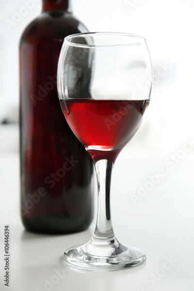 Fototapeta Glass of red wine with bottle on blurred interior background