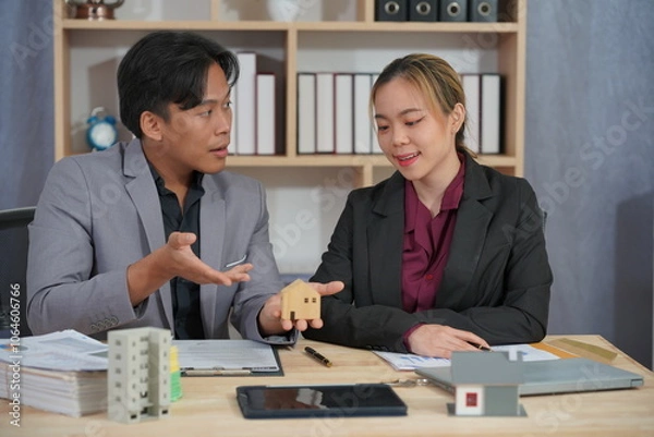 Obraz A real estate sales representative talks to explain real estate investment documents along with a home sales contract and home insurance to clients.