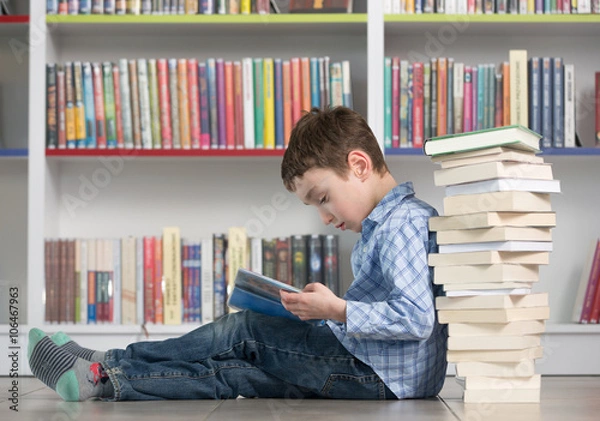 Obraz Ładny chłopak czytanie książki w bibliotece