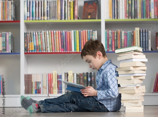 Obraz Cute boy reading book in library
