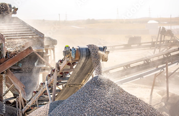 Obraz Vibrating screen stone crusher in operation. Crushing stones in a quarry for processing minerals, cement, limestone. Heavy and mobile equipment in a quarry for processing stone into building material.