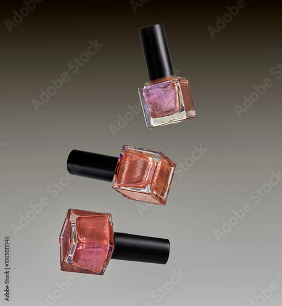 Fototapeta Different colored nail varnish bottles on a grey gradient background.