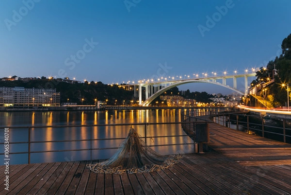 Obraz Fishing net laying on pier with illuminated Arrabida bridge at blue hour in afurada, Gaia, Porto, Portugal
