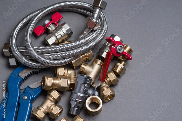 Fototapeta Adjustable spanner with assorted plumbing fittings and hose on grey