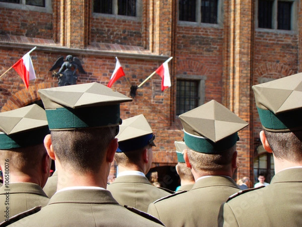Obraz Obchody majowe z okazji rocznicy uchwalenia Konstytucji 3 Maja. Żołnierze wojska polskiego stoją na toruńskim rynku, a w tle polskie, biało czerwone flagi.