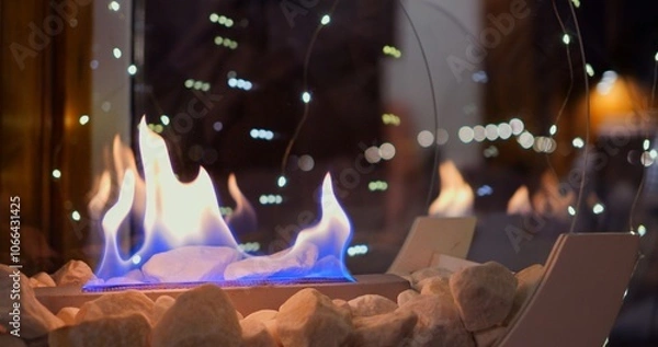 Obraz Christmas decorations with biofire create magical holiday atmosphere. warmth of flames paired with twinkling lights brings comfort and joy to winter celebrations. Bio fireplace at christmas