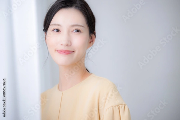 Fototapeta 明るい日差しの差すカーテンに寄りかかる女性　笑顔のカメラ目線