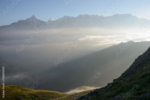 Fototapeta sunlit high mountains covered with fog