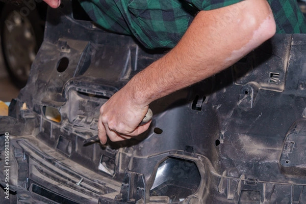 Fototapeta Mechanic working on car part with screwdriver