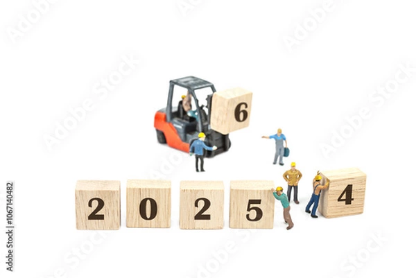 Fototapeta miniature worker team building standing front of forklift machine with 2025 number on wooden block on white background
