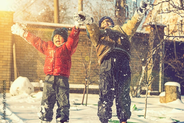 Fototapeta Two boys play with snow. Happy childhood. Brothers on a walk. two kids playing with snow. toned.
