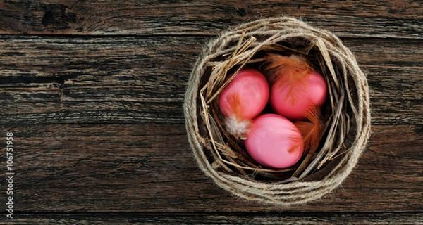 Fototapeta Easter pink eggs in nest on rustic wooden background